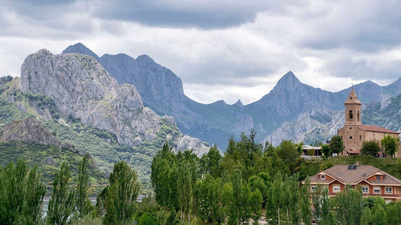 Steile bergtoppen en een stenen kerkje in het berglandschap bij de Picos de Europa tijdens een roadtrip Spanje.